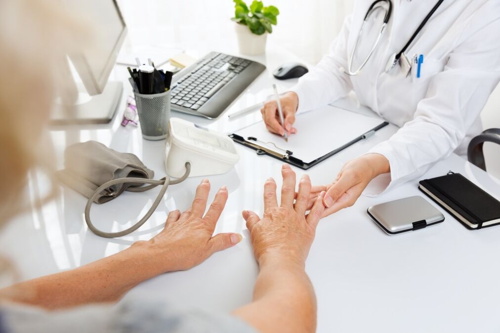 The doctor examines the hand with arthritis